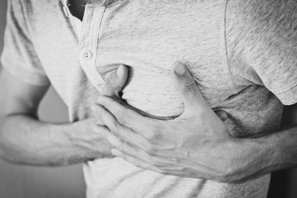 Black and white photo of a person holding their chest in discomfort